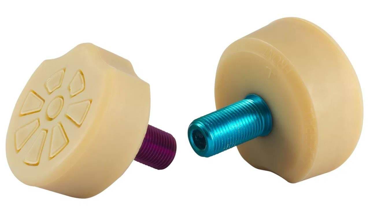 Two natural Gumball Superball Roller Skate Long 30mm Toe Stops feature textured tops for stability in roller derby, each with a colored threaded stem—one blue, one purple—shown on a white background.