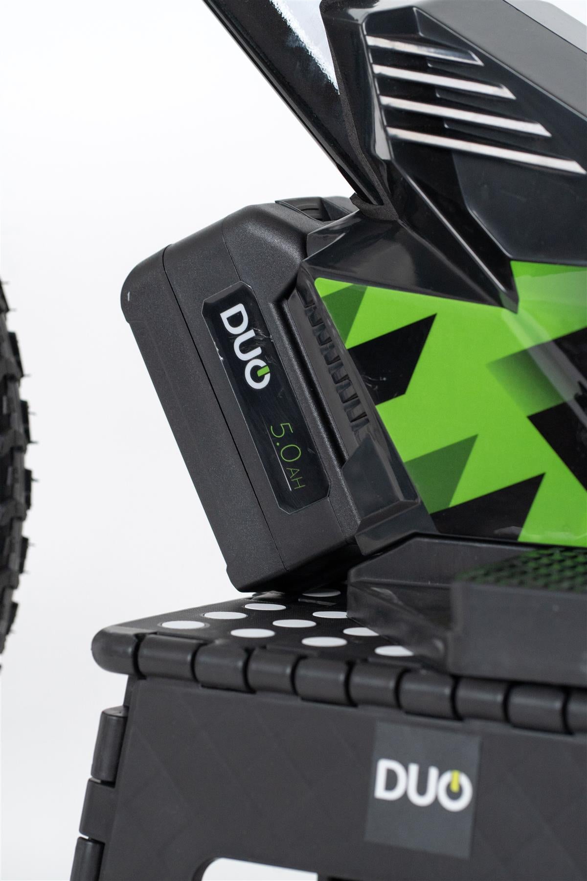 Close-up of the Duo 16" Master Pro Kids Electric Balance Bike in black and white, featuring a visible DUO 5.0Ah battery pack partially inserted on the side and a "DUO" logo on a black perforated platform below.
