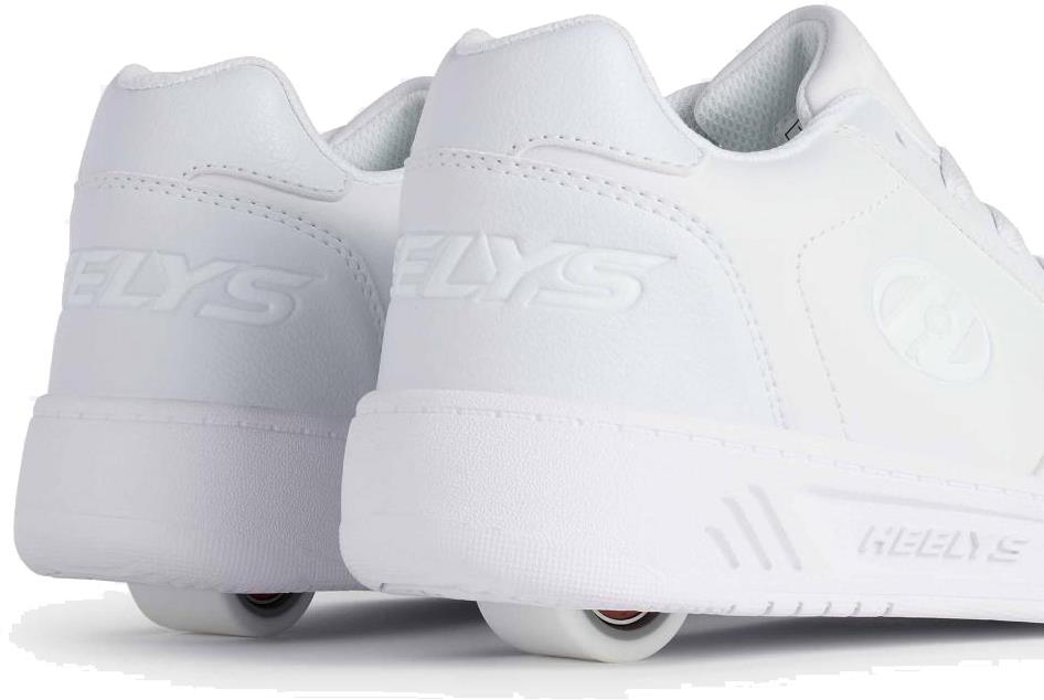 The Heelys Kama Girls Shoes in white feature low-profile wheels in the heels, blending classic court-style design with fun mobility. Shown from back and side views on a white background. Brand: Heelys.