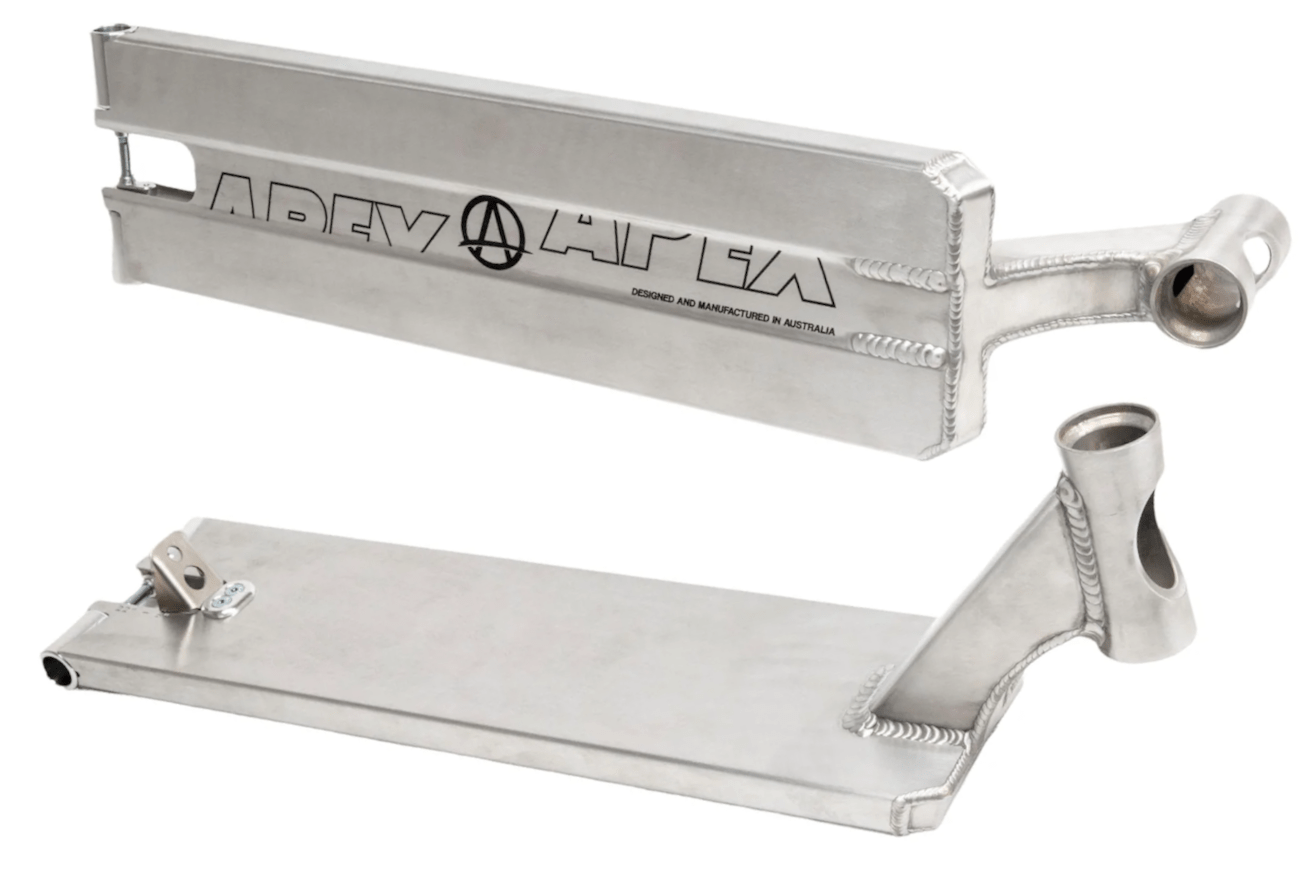 Two silver scooter decks are displayed. One, shown from a top view, features the Apex branding and logo for the Apex Pro Raw Silver Boxed Stunt Scooter Deck measuring 6" x 21", while the other highlights the underside and headtube. Made from durable aluminum, these decks showcase visible welds and smooth finishes, reflecting the quality of the Apex Deck range.