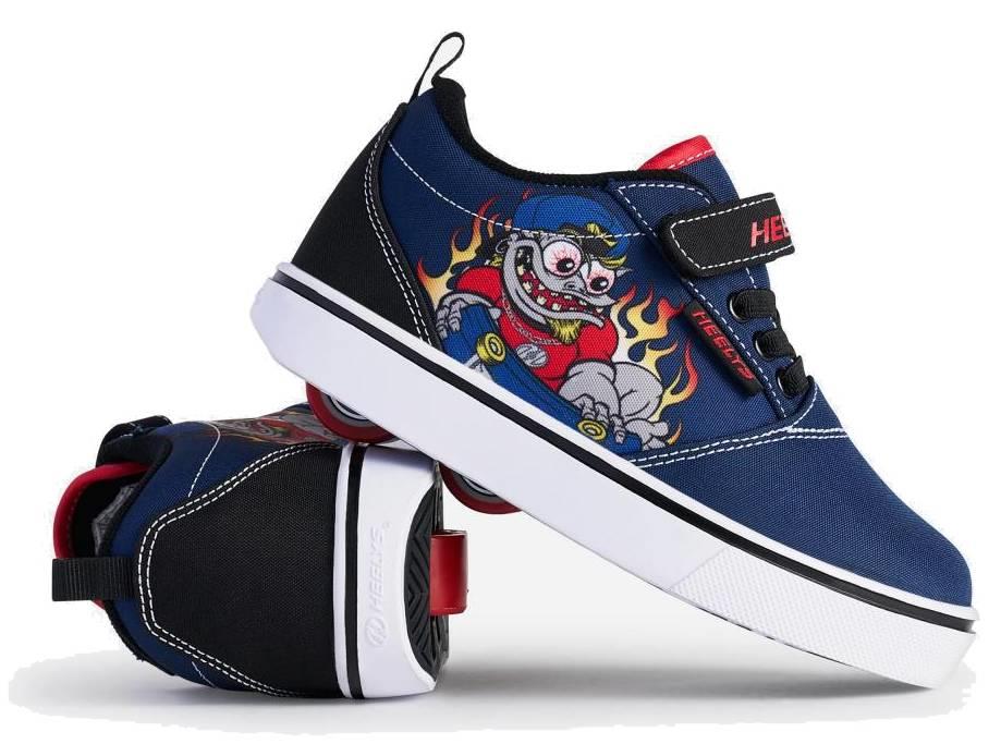 A pair of Heelys Pro 20 Prints X2 Boys Shoes in navy and red by Heelys, with white soles; one upright, one on its side displaying the wheel. Features a cartoon monster skateboarding with flames in the background.