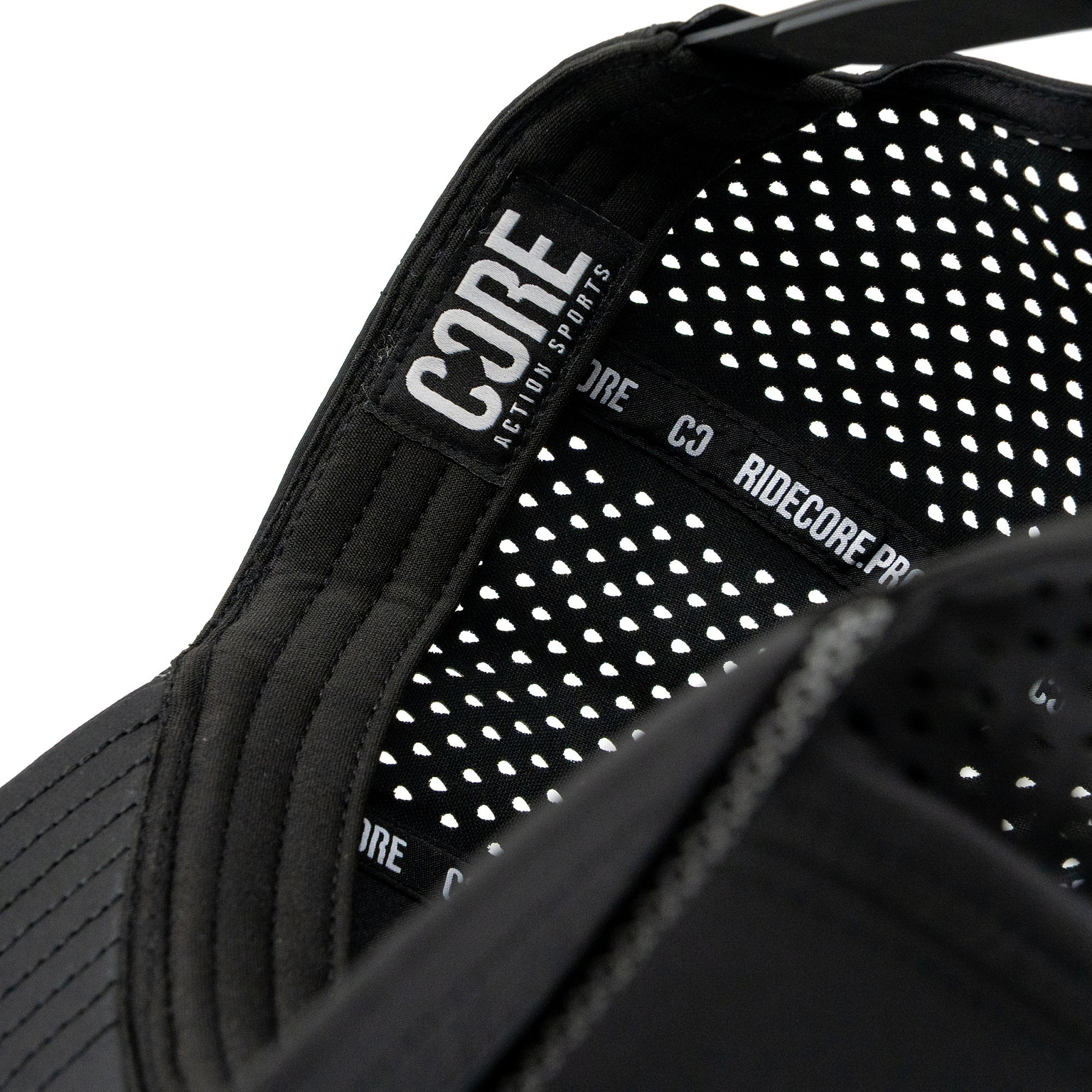 Close-up of the inside of the CORE Aero Rope Cap - Black, showcasing a signature CORE logo label and a patterned, perforated liner with “RIDECORE.PRO” text on the inner black band—attentive detailing that sets this premium performance cap apart.