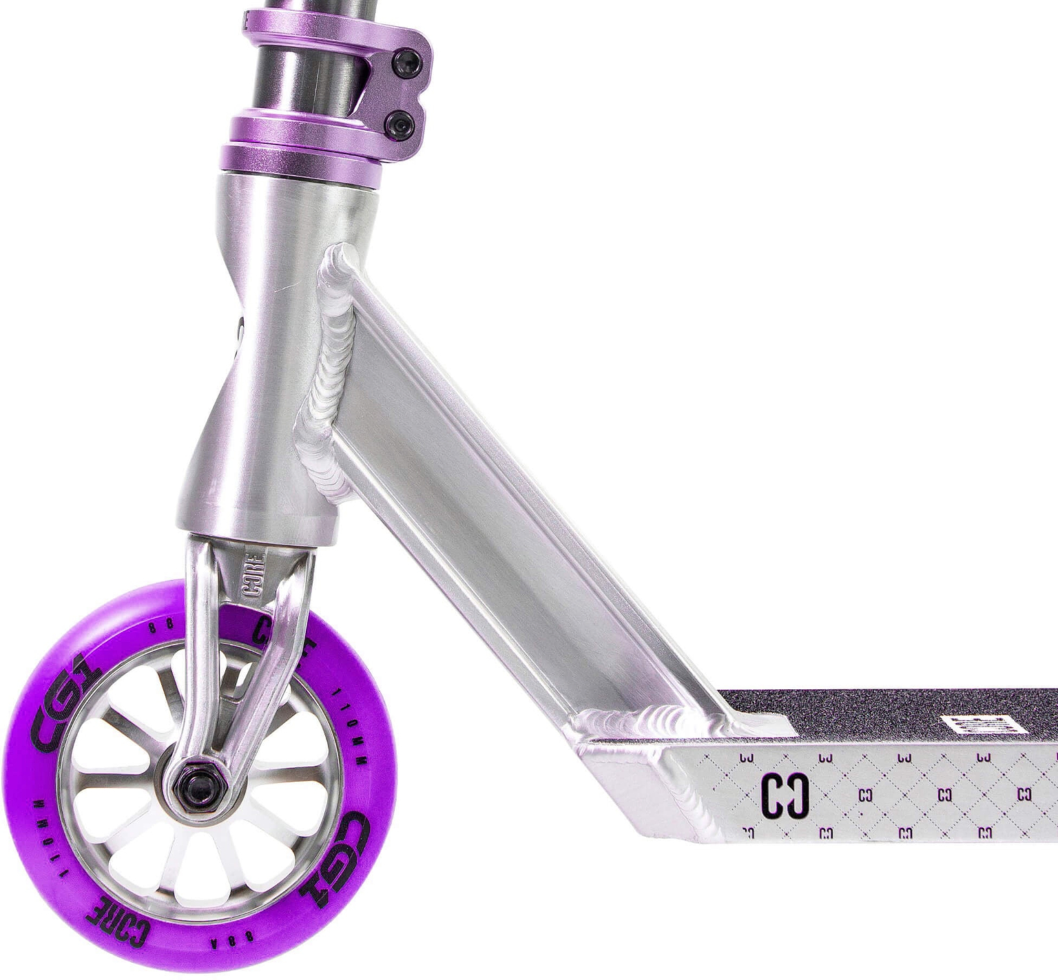 Close-up of the front section of the CORE CG1 Complete Stunt Scooter in Raw and Purple, showcasing a vibrant purple wheel. The deck displays a textured grip surface with geometric patterns, making it perfect for beginners learning tricks. The metallic Raw and Purple fork and clamp add to its striking appearance, capturing the signature sleek style of CORE scooters.