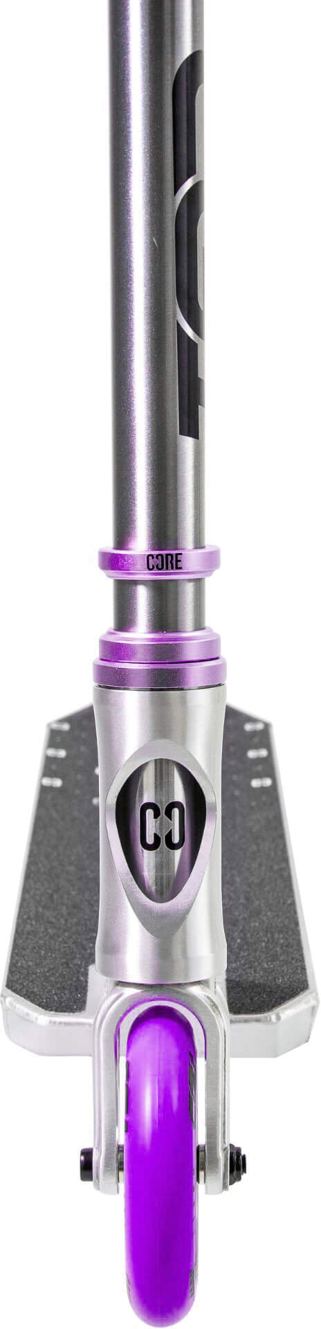 A close-up front view of the CORE CG1 Complete Stunt Scooter - Raw / Purple by CORE, a beginner-friendly stunt scooter in silver and purple, highlighting its vibrant purple wheel, black grip tape on the deck, and the “CORE” branding on both the headtube and clamp.