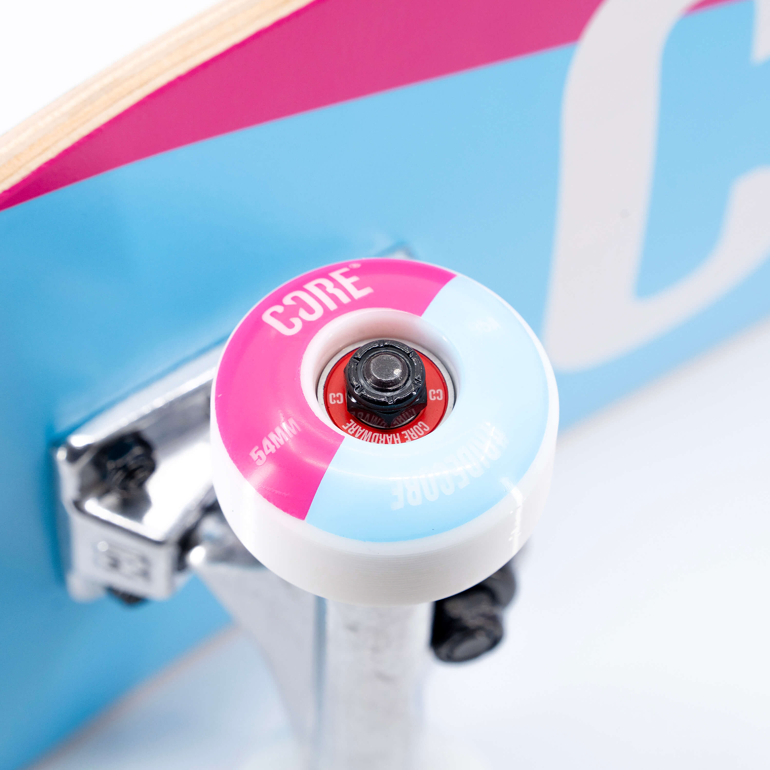 Close-up of a pink and blue split skateboard wheel on a silver truck, set against a matching CORE C2 Pink / Blue Split Complete Skateboard - 7.75″ x 31″ deck.