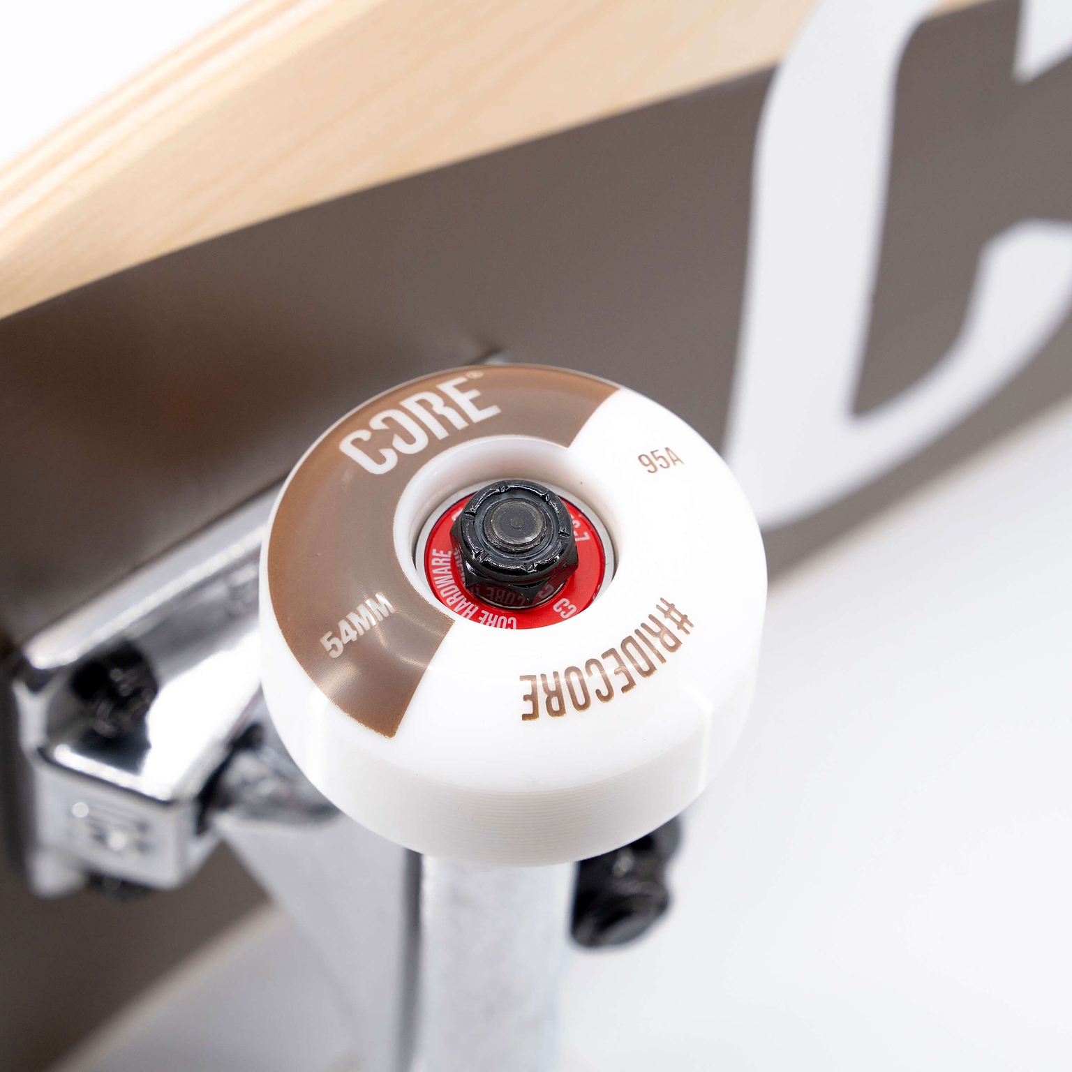 Close-up of a CORE C2 Raw Split Complete Skateboard wheel with white and brown detailing, mounted on a silver truck.