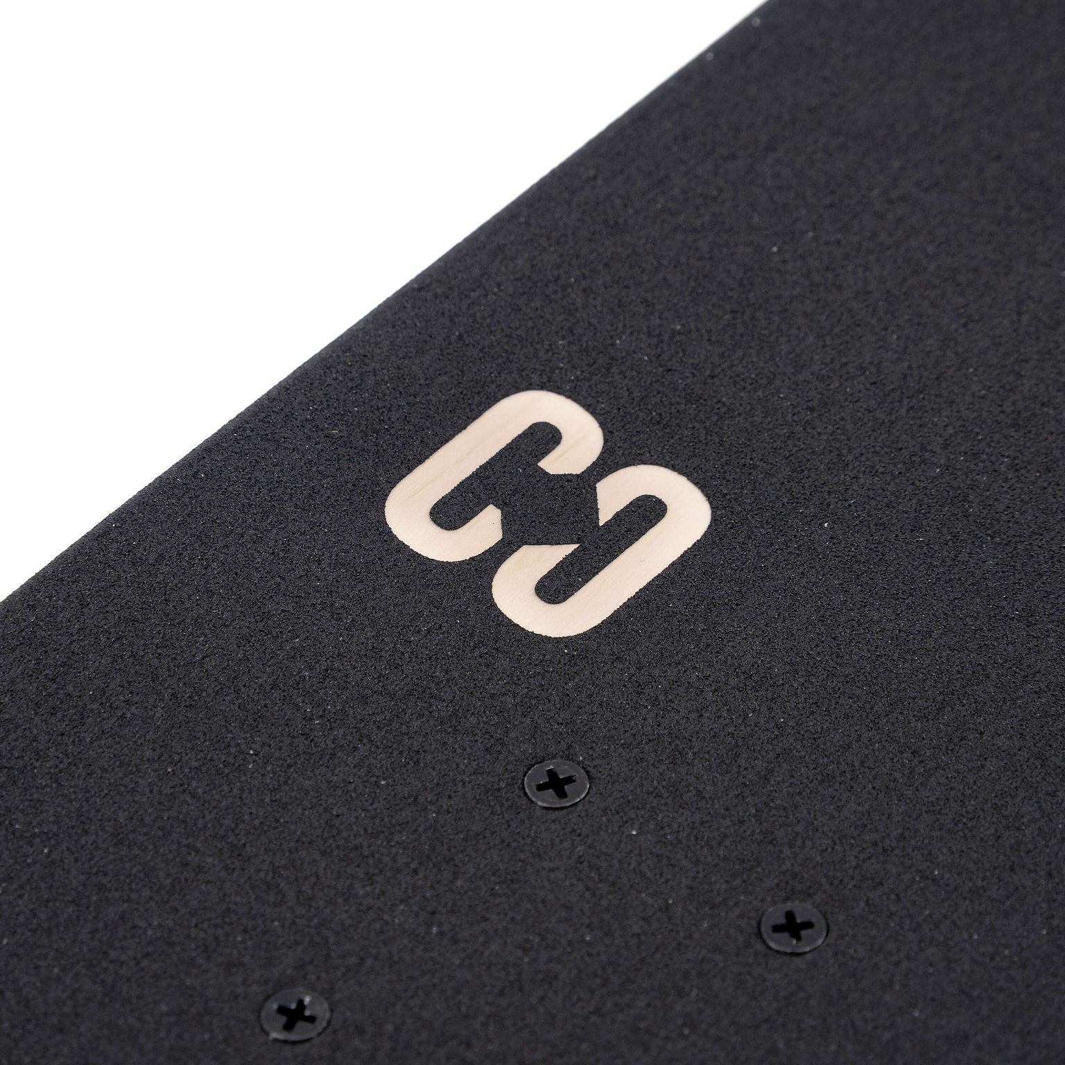 Close-up of black grip tape on a CORE C2 Red / Black Split Complete Skateboard - 7.75″ x 31″ maple deck, featuring a metallic C-shaped logo.