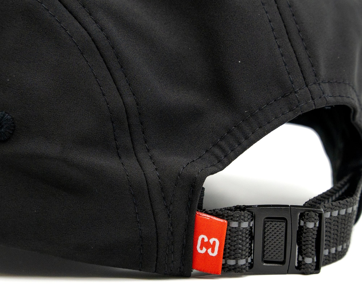 Close-up of the back of the CORE Performance Cap - Black / Reflective, featuring a black adjustable strap and a small red tag labeled “C3” near the opening, crafted from breathable fabric by CORE for all-day comfort.