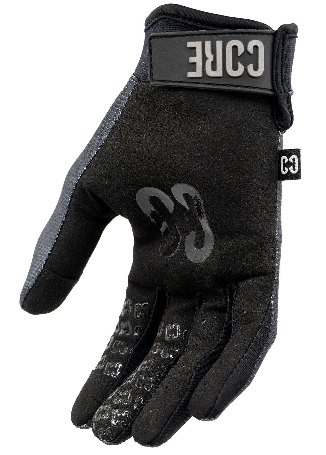 A single CORE Pro-Fit Velcro Skate Protection Glove in Reflective Black by CORE, designed for scooter riders, is shown palm up. It features a secure velcro strap, a visible CORE logo on the wrist, textured grip on the palm and fingers, and gray trim along the side.