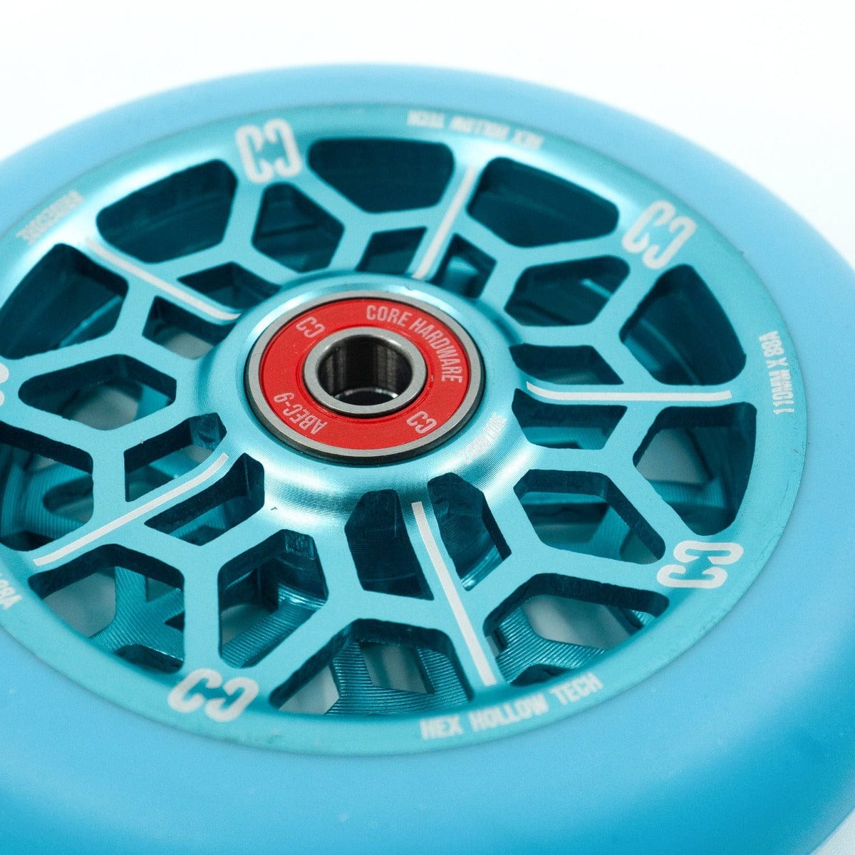 Close-up of the CORE Hex Hollow Core 110mm Stunt Scooter Wheel in Mint Blue, showcasing a red hollow core with a hexagonal pattern. White text around the wheel highlights model details, including HEX Hollow Tech and ABEC 9 Bearings specifications. The intricate spokes form a web-like design, ideal for stunt scooters.
