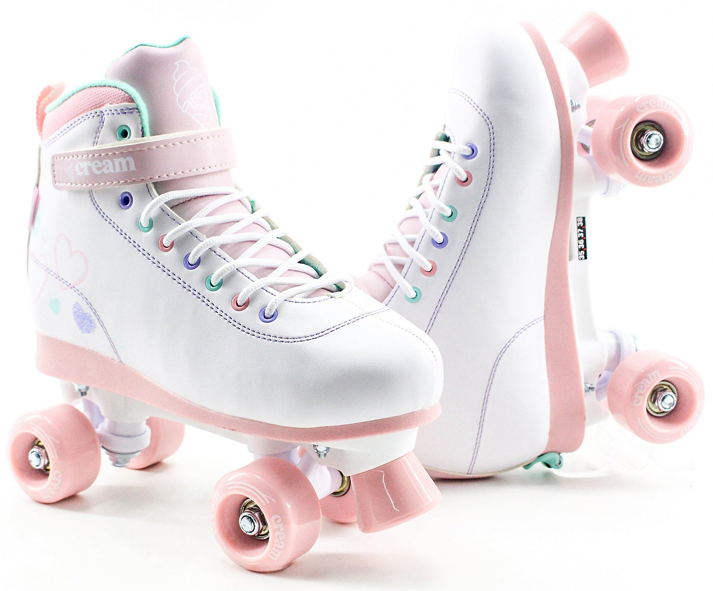 Presenting the CREAM Scoop Hearts Adjustable Quad Roller Skates in White and Pink—crafted from vegan leather, featuring pastel details, rainbow eyelets, and a signature "CREAM" strap. Designed for beginners, these stylish and functional quad skates are showcased in a pair against a white background.