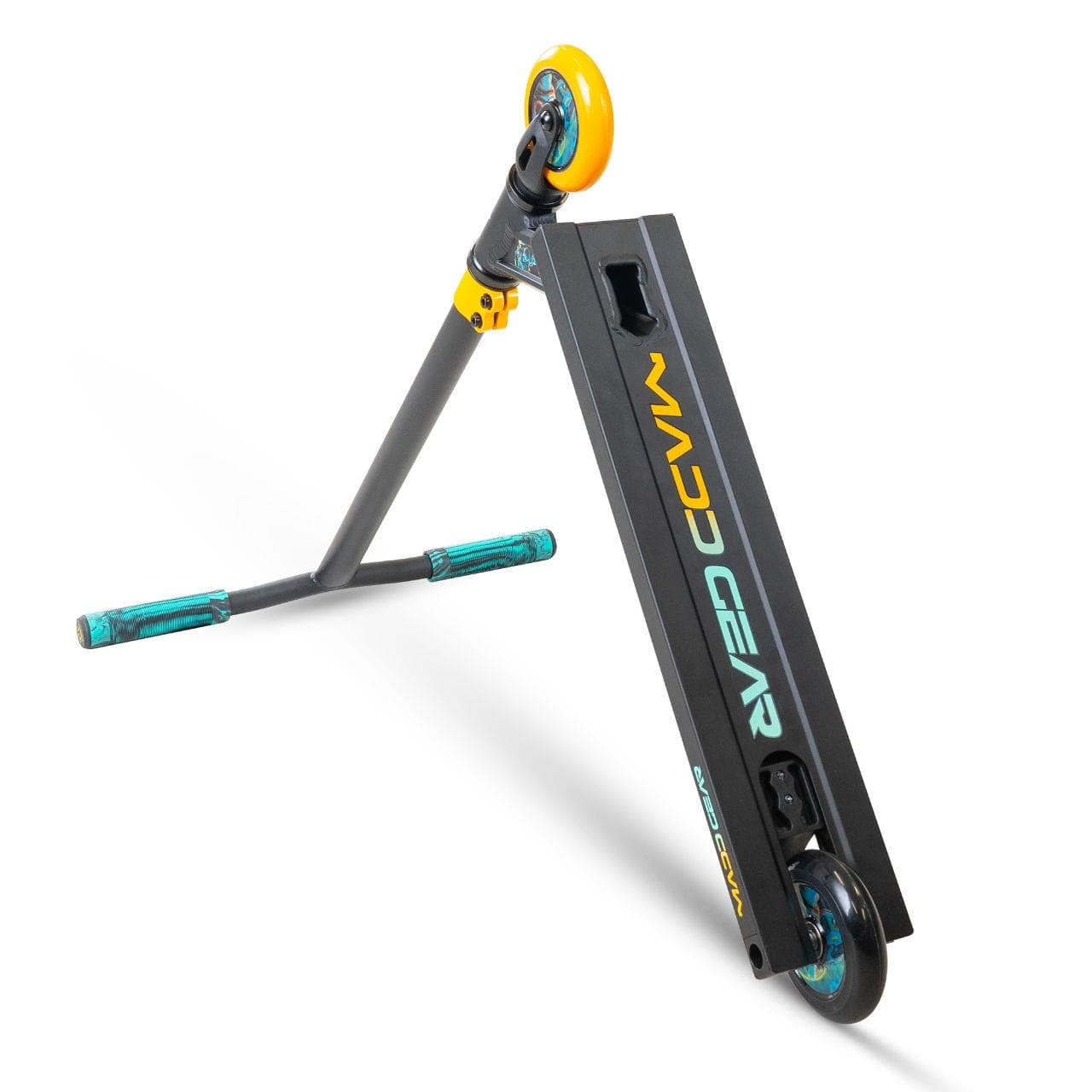 The Madd Gear MG 2 Obsidian Complete Stunt Scooter - DJ Rilla by MGP, in black and yellow with teal grips and ABEC-5 chrome bearings, is propped on its handlebars and rear wheel, showing the "MADD GEAR" logo on the deck.