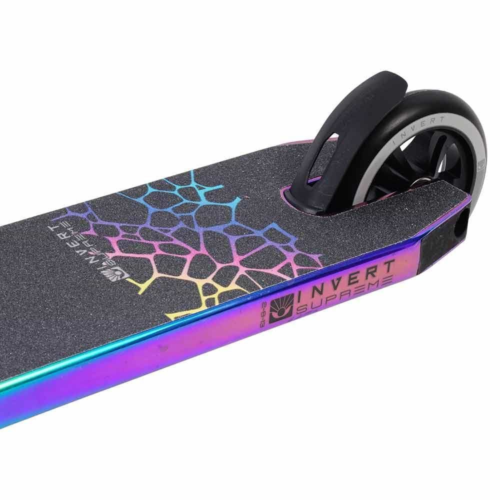 Close-up of the rear deck and wheel of the Invert Supreme 2-8-13 Complete Stunt Scooter - Neochrome, featuring geometric rainbow-patterned black grip tape and metallic neochrome deck edges. Designed by Invert for kids aged 8–13.