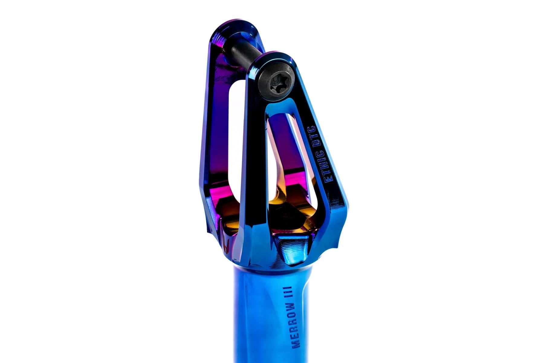 A close-up of the Ethic DTC Merrow V3 SCS Stunt Scooter Fork by Ethic, crafted from 7075 aluminium. The chrome blue fork features "MERROW III" labeling, cutouts, a top bolt, and a shimmering gradient finish—one of the lightest forks available.