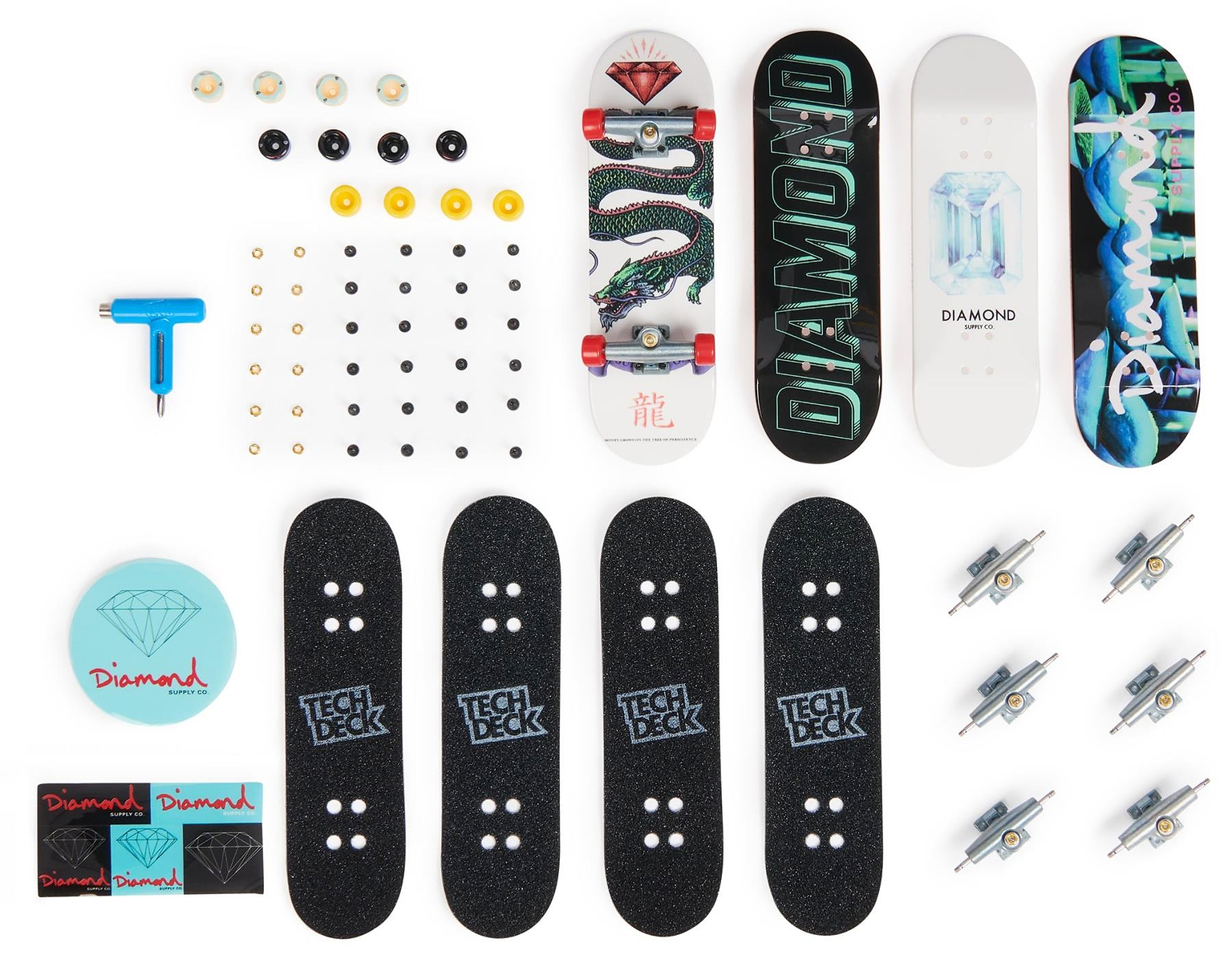 The Tech Deck M01 Deluxe 4 Pack Fingerboards - Diamond includes four authentic fingerboards with skateboard graphics, grip tapes, trucks, wheels, tools, stickers, and a blue carrying case by Tech Deck—displayed on a white background.