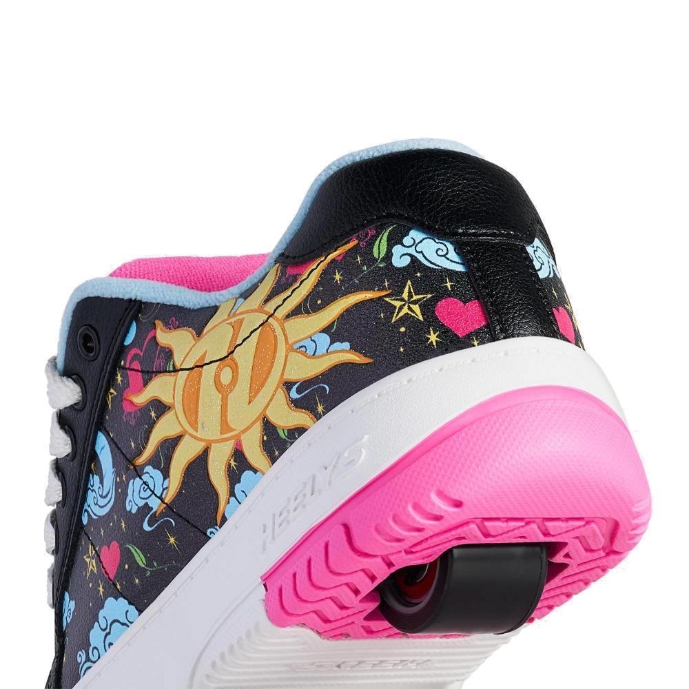 A close-up of the Heelys Kolect Prints Girls Shoes — Black / Blue / Neon Pink by Heelys, featuring a retractable wheel and colorful glow-in-the-dark designs with suns, clouds, hearts, and stars on black and a pink sole.