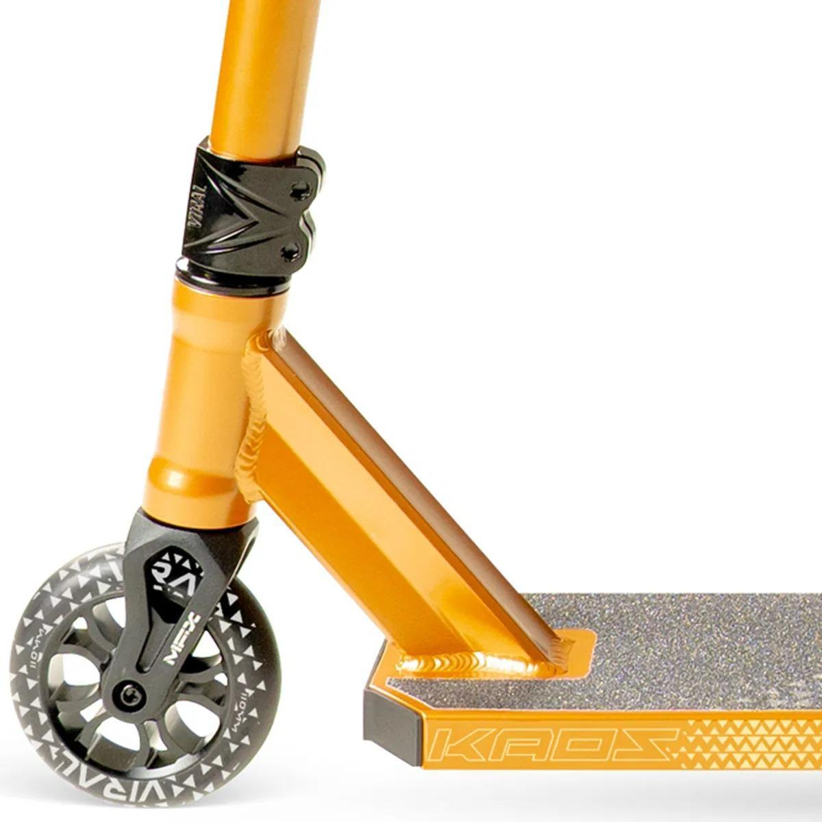 Close-up of the front part of the Madd Gear (MGP) Viral KAOS Complete Stunt Scooter in Copper, highlighting the handlebar clamp, black and gray patterned front wheel, and textured deck with "KAOS" on the side.