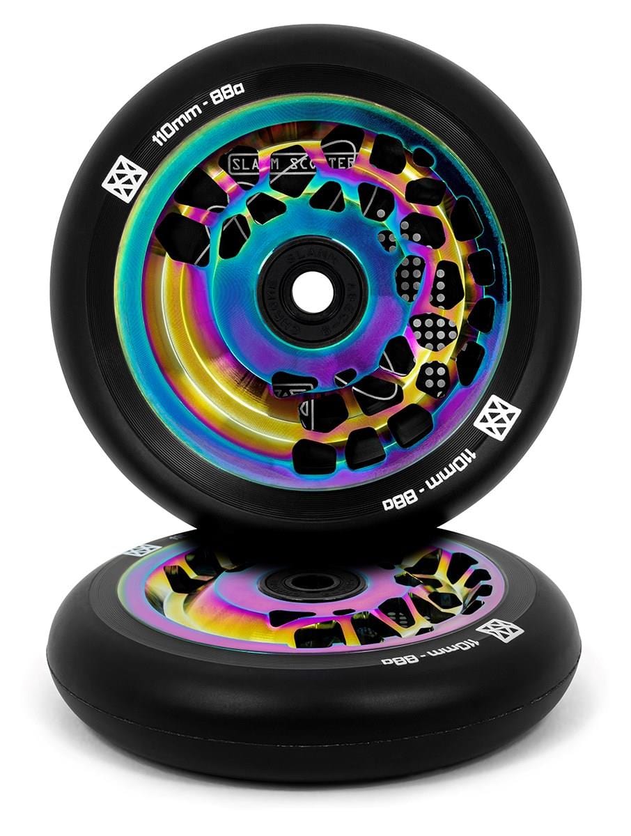 A pair of eye-catching Slamm Split Core 110mm stunt scooter wheels features a colorful neochrome finish with an iridescent core, showcasing contrasting designs on black rubber. The edges display "110mm Split Core - 88a" alongside the Slamm brand logo. One wheel rests against the other.