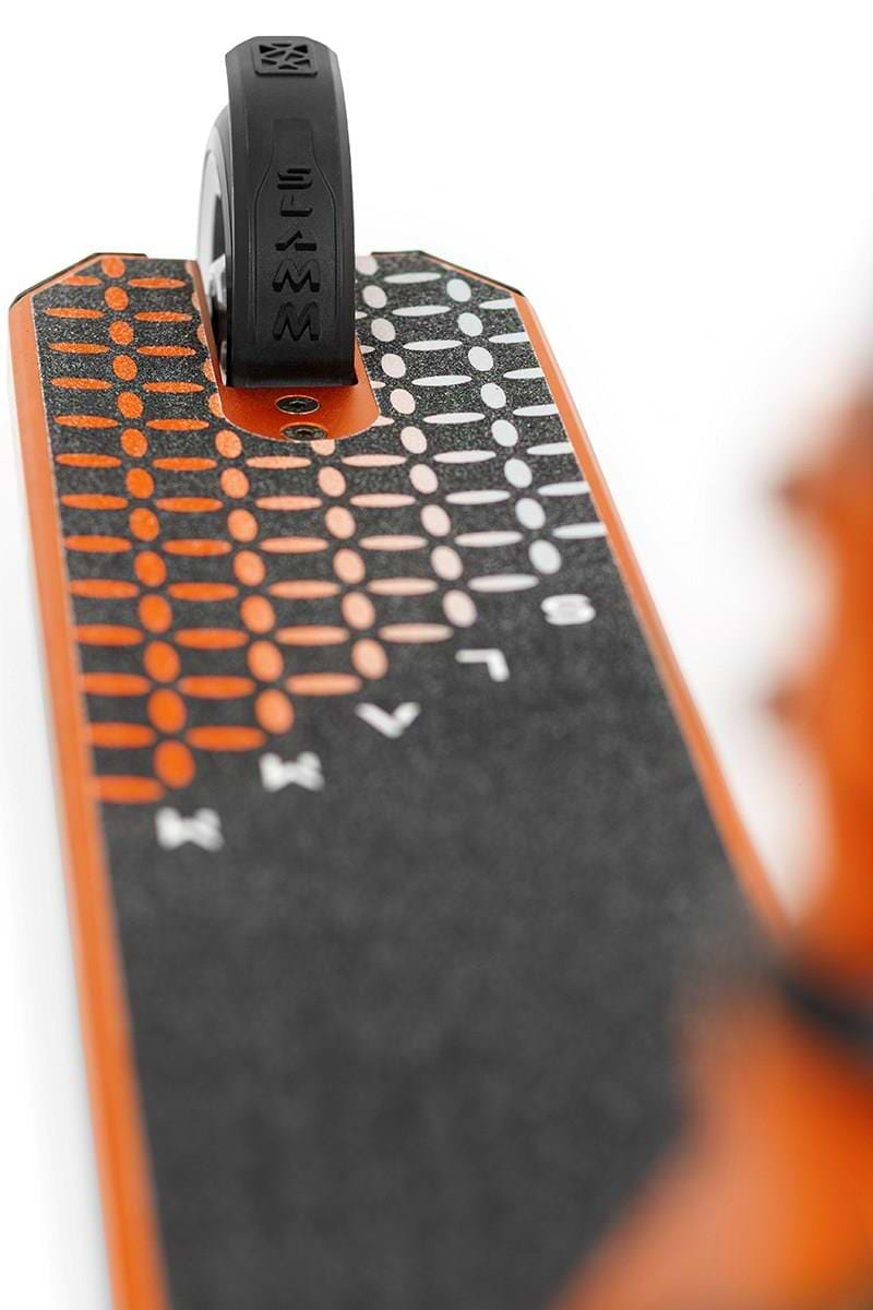 Close-up of the Slamm Assault Complete Stunt Scooter - Orange deck, showcasing a black and orange dotted grip. The aluminum wheels peek through, highlighting their sleek and modern design, ideal for skill-focused riders.