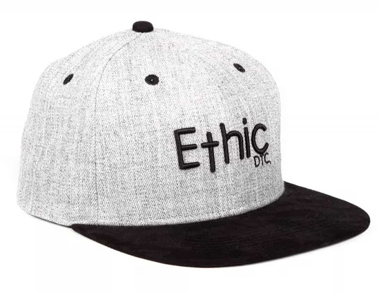 The Ethic DTC Snapback Cap - Deerstalker Grey showcases a timeless snapback style, featuring a gray crown paired with a black brim. The front prominently displays the word "Ethic" embroidered in black, while the smaller letters "DTC" are artistically positioned below, emphasizing its distinctive embroidered Ethic logo.