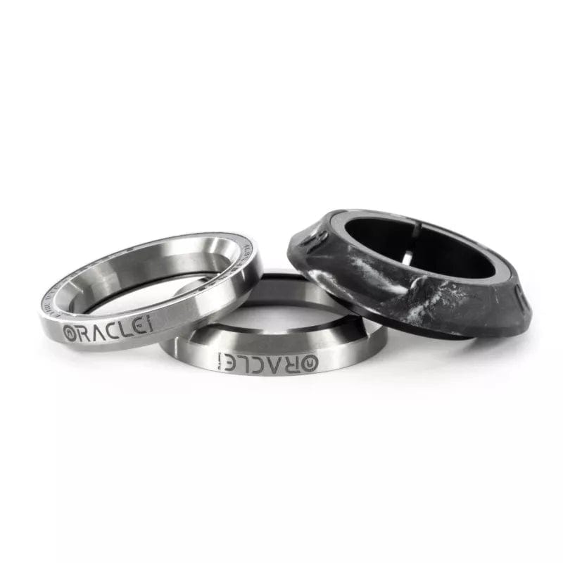 The Ethic DTC Osmose Silicone Integrated Stunt Scooter Headset - Grey features three meticulously designed metal rings stacked together. Two of these rings are smooth and silver with "ORACLE" engraved on them, while the third is a matte black with a textured finish. They are beautifully presented against a white background.