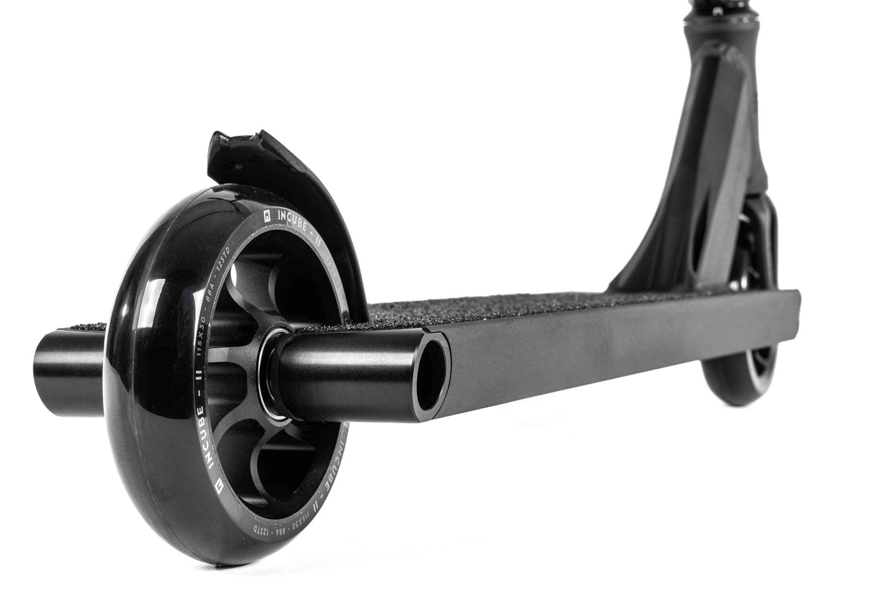 Close-up of a black wheel on the sleek, minimalist deck of the Ethic DTC Pandora Complete Stunt Scooter (M) - Black. The wheel features a sturdy metal core and glossy finish. With its textured surface for enhanced grip, this scooter from Ethic is ideal for urban adventures.