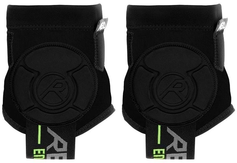 A pair of REKD Energy Covert Ankle Impact Skate Protection Guards in black with energy-absorbing padding and green-accented elastic straps, displayed side by side against a white background.
