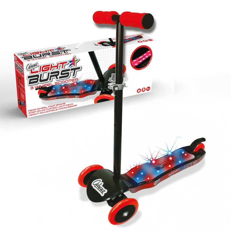 The Ozbozz Light Burst Light Up Kids Tri-Scooter in black and red boasts a vibrant light-up deck with red and black highlights. The handlebar is equipped with red grips, and three robust wheels provide smooth riding experiences. In the background, a coordinating box displays product images along with colorful graphics.