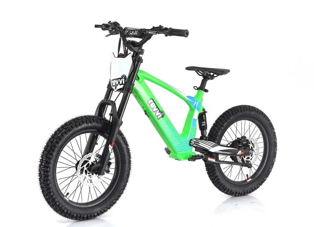 The Revvi 18" Kids Electric Balance Bike in green features thick black tires and a robust frame. Designed with young adventurers in mind, it boasts hydraulic disc brakes, a front suspension fork, and a comfortable seat, while the Revvi brand name is prominently displayed on the frame.