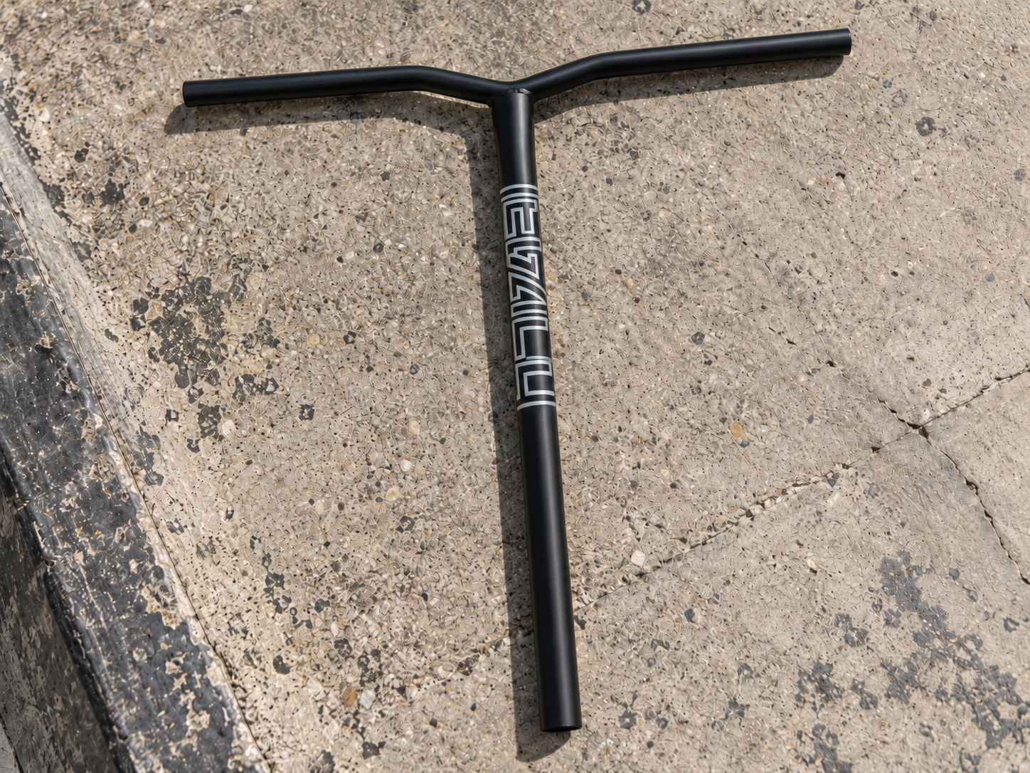 Black Legacy Ventus Steel Standard IHC Stunt Scooter Bars with white text on the vertical tube, resting on a concrete surface.