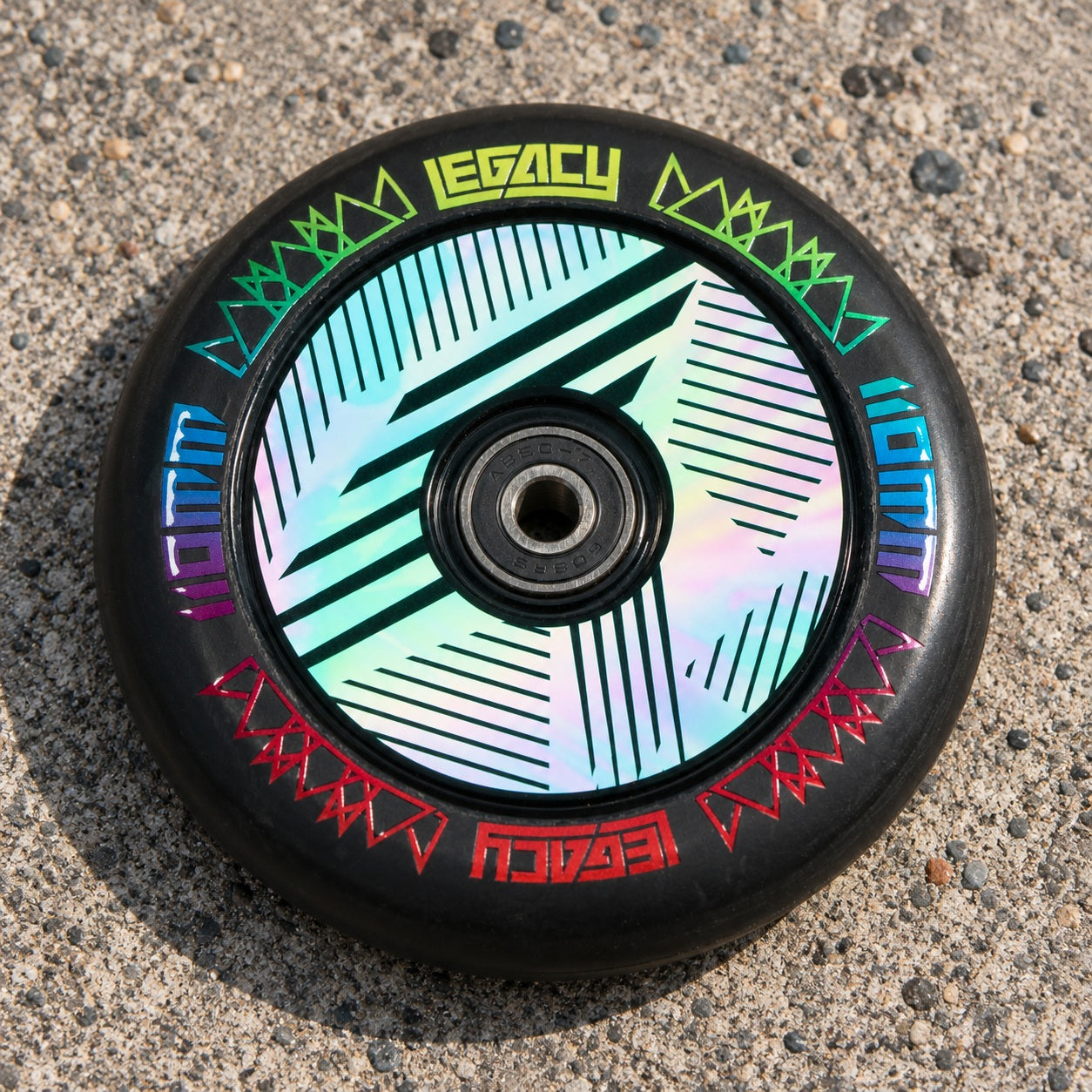 Legacy Ventus 1.5 Pro 110mm Stunt Scooter Wheel in neochrome, featuring a black rubber tire and a hollow core with geometric patterns and colorful text accents.