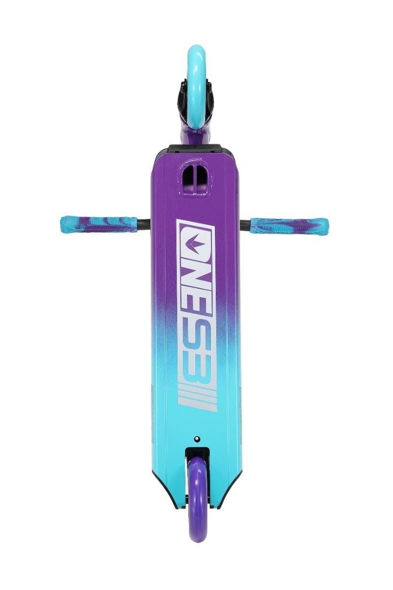 Seen from above, the Blunt Envy ONE S3 Complete Stunt Scooter in Purple/Teal displays a striking gradient design that shifts from purple at the top to turquoise at the bottom. The deck prominently showcases "ONE3" in bold white letters and is equipped with durable pro scooter components, including teal and purple handles and wheels.