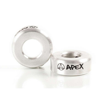 Two raw silver, circular metal BMX headset spacers with a hole in the center display the word "APEX" alongside an anarchy symbol in black. One spacer stands upright while the other rests on its side against a white background, enhancing your scooter accessories collection similarly to the Apex Aluminium Scooter Bar Ends - Raw Silver.