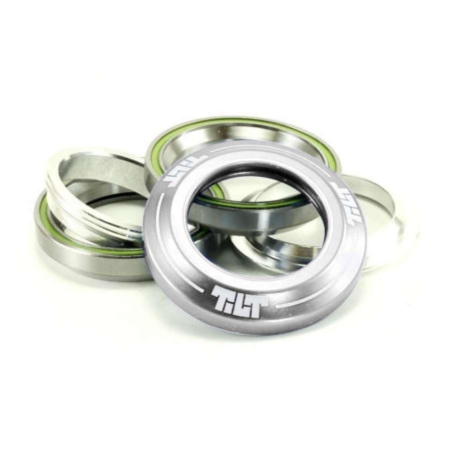 The Tilt Integrated Stunt Scooter Headset - Silver by Tilt features silver bearings and anodized dust covers, with the main bearing cover displaying the "TILT" logo, all arranged slightly overlapping on a white background.
