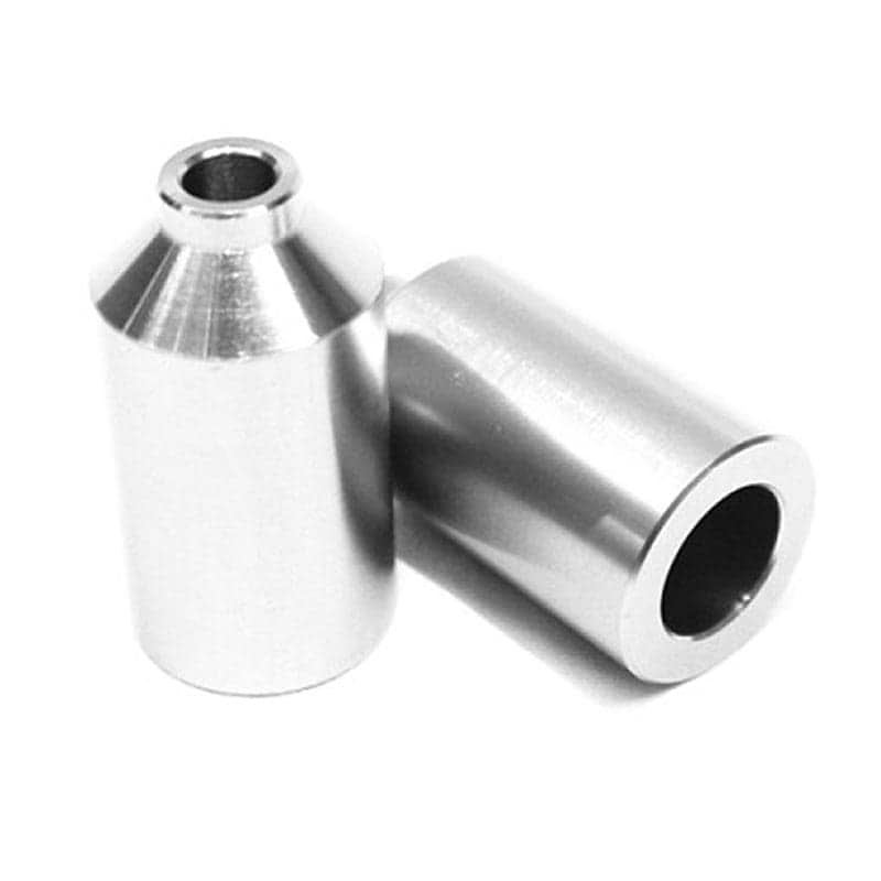 Two chrome silver metal cylindrical objects with a smooth, polished surface are featured. One stands upright with a hollow center, while the other leans against it at an angle. These are the Blunt Envy Aluminium Stunt Scooter Pegs, ideal for both park and street riding. The scene is set against a plain white background.