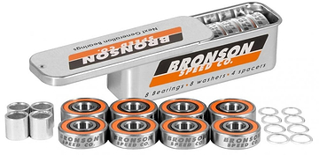 Inside the metal box featuring "Bronson," you will find Bronson Speed Co. G3 Skateboard Bearings - 8 Pack, alongside washers and spacers. The high-speed ceramic oil guarantees peak performance for the deep groove raceways. Stylishly accented in orange and black, these bearings are arranged in two tidy rows next to the open box.
