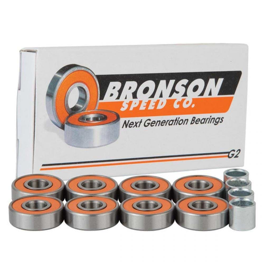 An eight-pack of Bronson Speed Co. G2 Skateboard Bearings, featuring orange seals, is displayed in front of their box, which reads "Next Generation Bearings." These bearings are designed with deep groove raceways and enhanced with high-speed ceramic oil for superior performance. Additionally, three spacer components are included.