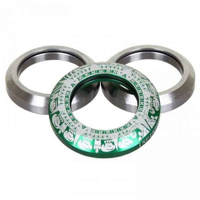 Three circular metal objects are shown. Two silver rings are positioned at the back, while an Infinity Mayan Integrated Stunt Scooter Headset in green, featuring intricate white patterns, is placed in front. This green headset resembles a CNC-milled piece and showcases decorative designs around its circumference akin to those found on a stunt scooter headset.