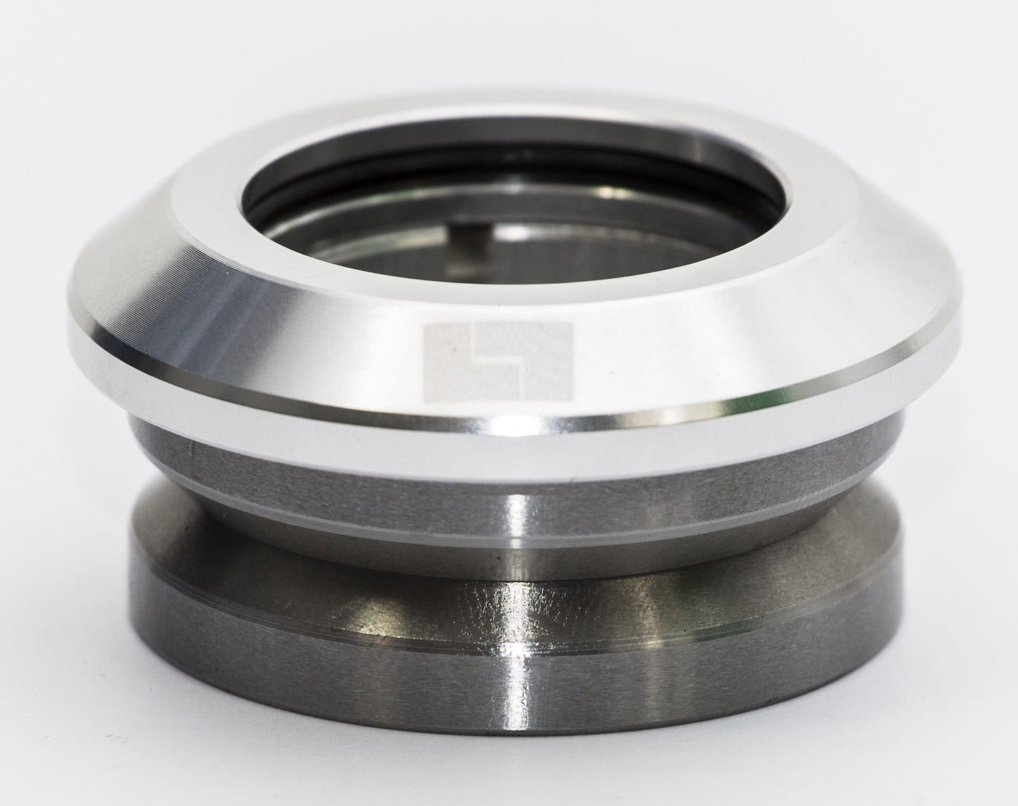 Close-up of the Logic Integrated Stunt Scooter Headset in silver, a metallic mechanical component with a smooth, shiny surface and a hollow center. This circular piece is set against a plain white background, highlighting its precision design.