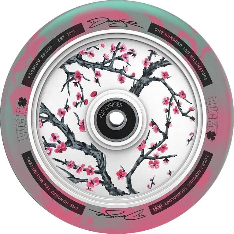 Presenting the Lucky Lunar 110mm Stunt Scooter Wheel - Darcy Cherry Evans Signature V3, adorned with cherry blossom artwork on the rim. The pastel green and pink background beautifully complements scooter builds, while various texts provide brand and size details. Experience a smooth ride with Lucky Rebound Technology™.