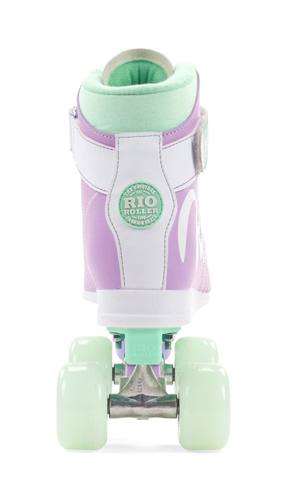 The Rio Roller Milkshake Quad Roller Skate - Mint Berry features a pastel-style design reminiscent of a classic trainer skate, showcasing its purple and white boot with mint green wheels and a padded mint green opening. The back of the skate prominently displays the "Rio Roller" logo above the heel, beautifully embodying the essence of Rio Roller's charming Milkshake series.