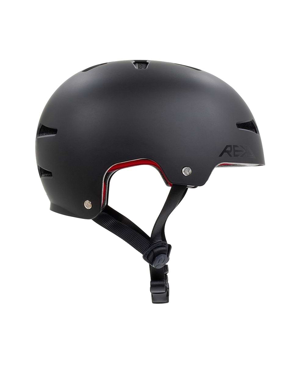 Introducing the REKD Elite 2.0 Skate / Scooter Helmet in Black, featuring a matte finish and smooth, rounded design. This certified helmet offers ventilation slits, a red inner lining, and an adjustable black chin strap with a buckle, ideal for action sports enthusiasts who prioritize both style and safety.
