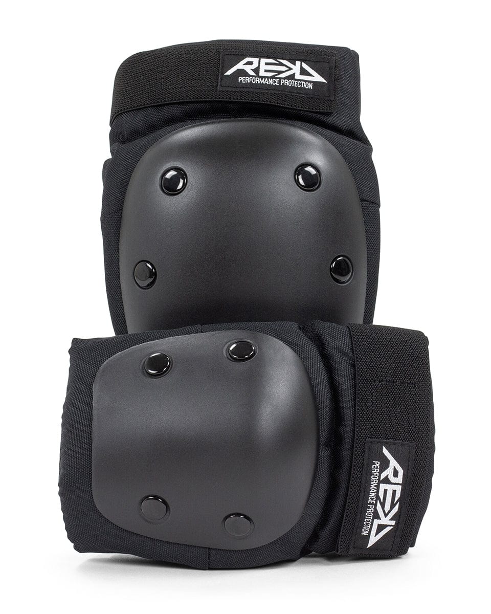 The REKD Youth Heavy Duty Double Skate Protection Pad Set in black offers superior protection with its hard shell caps and elastic straps, tailored for performance. The prominent "REKD" brand logo is displayed on the top of each pad, making it an excellent choice for action sports enthusiasts seeking dependable equipment.