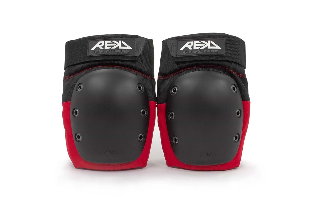 A pair of REKD Ramp Knee Skate Protection Pads in black and red, featuring hard black caps with the "REKD" logo on top. Designed for action sports, these knee pads provide impact resistance suitable for skateboarding and rollerblading.