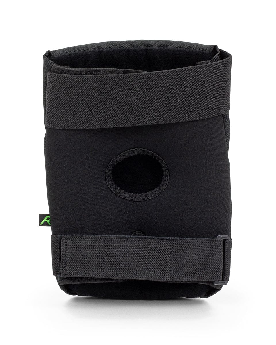 A pair of REKD Energy Ramp Skate Protection Knee Pads in black, designed with adjustable straps and an open patella design, stands upright against a white background. Integrated with impact foam, they provide enhanced support and protection during physical activities. Ideal for those seeking the reliability of the REKD brand.