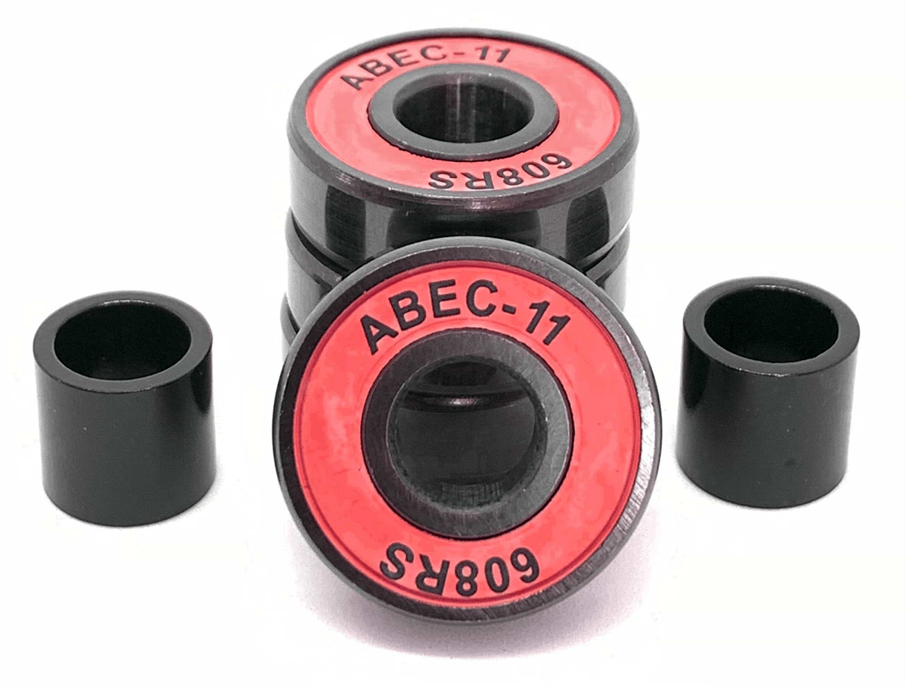Close-up of four Logic ABEC 11 Red Scooter Bearings stacked on a white surface, ideal for performance speed enthusiasts. Two additional black cylindrical spacers are positioned on each side of the stacked bearings.