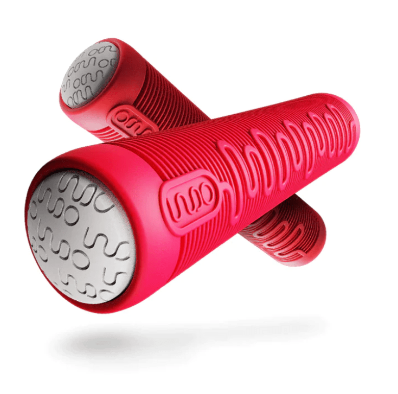 The two cylindrical red foam rollers, resembling the INDO V2 Stunt Scooter Grips - Red Rocker, have textured surfaces and silver metal end caps adorned with raised wave patterns. Positioned on a white background, they capture the dynamic design of an INDO Trampoline Scooter for enhanced control during use.