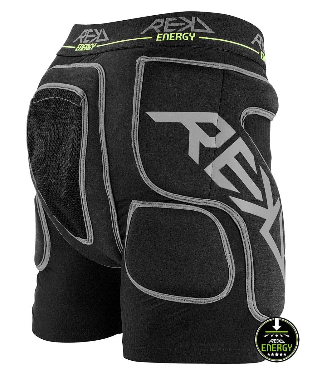 Introducing the REKD Energy Impact Skate Protection Shorts - Black: These padded protective shorts are designed with gray details and feature prominent "REKD" branding. They include mesh fabric on the hip area and a coccyx bone protector to ensure maximum impact protection. The waistband is adorned with a green "Energy" logo, and the lower right side showcases a distinctive downward arrow rating emblem.