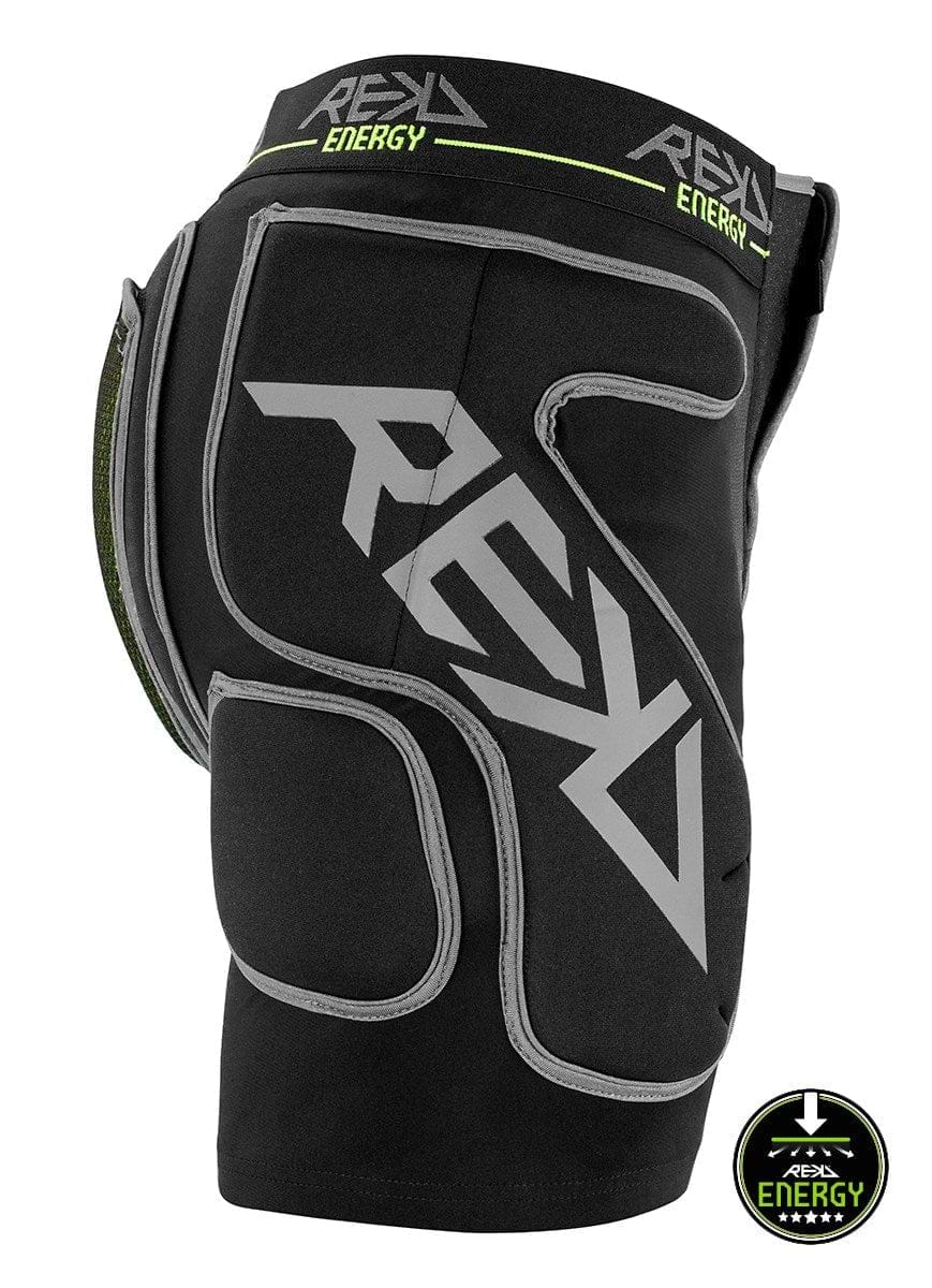 The REKD Energy Impact Skate Protection Shorts - Black feature black padded crash pants with gray branding and logos, offering protective padding on the sides and back. These shorts include a coccyx bone protector for enhanced safety, with a small circular "Energy" logo at the bottom.
