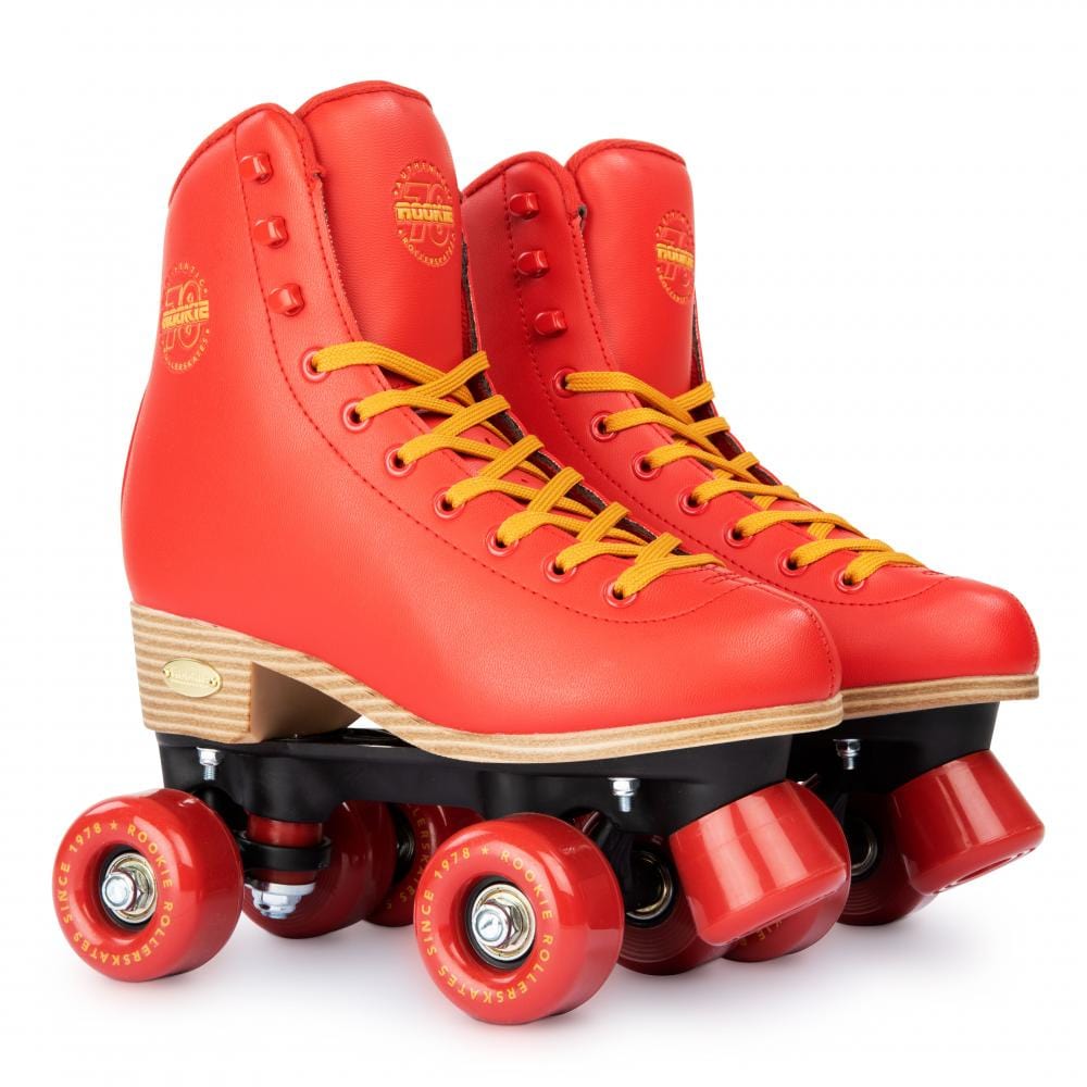 A pair of Rookie Classic 78 Quad Roller Skates in a vibrant red color, featuring yellow laces and red wheels set against a white backdrop. These skates by Rookie boast a vintage design with wooden soles and are crafted to be vegan-friendly.